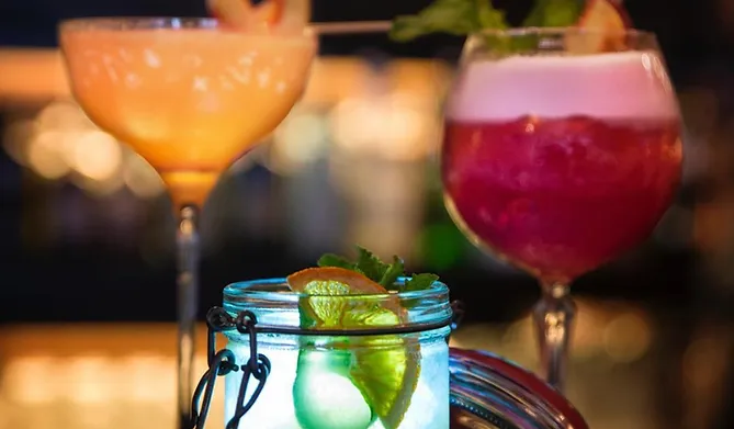 Mehrere bunte Cocktails in verschiedenen Gläsern.